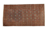 Distressed vintage Belouch runner, showing wear and repeating octagonal geometric guls in muted red and blue.