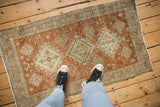 Distressed hand-knotted Heriz rug showcasing worn terracotta and faded blue geometric patterns.