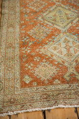 Distressed texture of vintage Heriz rug, with burnt orange field and green border patterns.