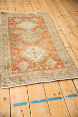 Distressed Heriz rug corner showing intricate border, terracotta field, and pale blue accents.
