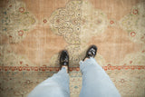 Vintage distressed Kashan rug, showing its dusty rose field, curvilinear patterns, and worn texture underfoot.