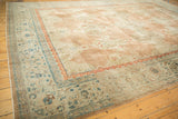 Distressed vintage Kashan carpet corner, featuring dusty teal vine border and brick red scrolls.
