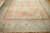 Distressed Kashan rug close-up: red scrolling border, dusty teal floral motifs, ribboned cloudbands.