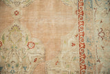 Muted dusty rose and brick red distressed Kashan carpet pile texture.