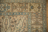Close-up on the worn corner of a vintage Tabriz carpet with beige and pale blue geometric vines.