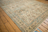 Angled corner view of the distressed Tabriz carpet, showing worn pile and pale blue floral vines.