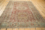 Angled view of a vintage Karaja rug highlighting its overall distressed pattern and geometric medallions.