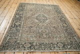 Distressed Karaja rug detail showing geometric motifs and textured pile in charcoal, sand, pale blue.