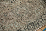 Distressed vintage Karaja rug detail: geometric serrated leaf and hook motifs in beige, charcoal, pale blue.