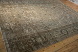 Angled view of a distressed Persian rug showing its time-softened neutral tones and low-pile texture.