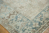 Low-pile corner of a distressed rug with a Turtle Samovar border in soft blue and beige.