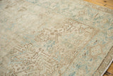 Angled view of the distressed Mehrivan carpet's low pile, showing geometric motifs in beige and powder blue.