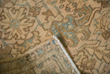 Folded corner revealing the hand-knotted back and secured side cord of the distressed rug.