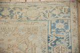 Distressed vintage Heriz rug corner, showing worn beige field and dusty blue turtle motif border.