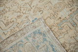 Detail of a folded distressed Heriz rug, showing worn beige pile and dusty blue woven foundation.