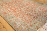 Angled view of a vintage Heriz carpet showing its ruby red field and dusty blue border.