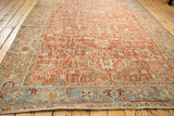 Long perspective of a distressed Heriz carpet showing the ruby red geometric field and blue turtle border.