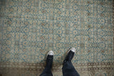 The distressed texture and repeating Herati motif of a vintage Tabriz carpet in dusty blue and sand.