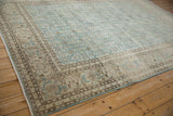 Angled view over the beige and brown floral border of a vintage distressed Tabriz carpet.