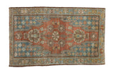 Vintage distressed Mazlaghan rug with a cochineal red field, blue serrated spandrels, and floral motifs.