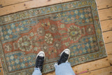 Overhead view of a vintage Mazlaghan rug showing its even wear and decorative pattern.