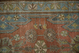 Dusty blue serrated corner spandrel over the cochineal red field of a vintage Mazlaghan rug.