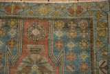 Distressed Mazlaghan rug corner with a serrated spandrel and a meandering vine border.