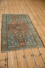High angle view of a vintage Mazlaghan rug with a red floral field and blue serrated spandrels.