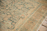 Even wear across the distressed pile, showing dusty teal and coral floral sprays near the border.