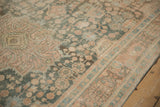 Angled view of the distressed Hamadan rug's low pile and faded floral patterns.