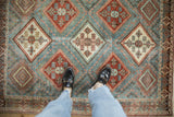Distressed vintage Afshar rug with rust and ivory diamond guls set in a dusty sky blue lattice.