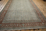 Rust turtle motif border running the length of a distressed Tabriz carpet with a dusty teal field.