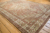 Corner view of a distressed Baktiari carpet's floral border and time-softened low pile.