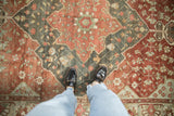 Distressed Baktiari carpet showcasing burgundy, dusty teal, and blush floral patterns underfoot.