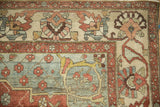 Distressed Baktiari carpet corner detail, showing floral bell blossoms, dusty teal, red, and beige colors.
