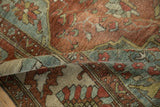 Folded vintage Baktiari carpet showing distressed burgundy, dusty teal, and beige floral patterns.
