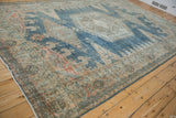 Angled view of a distressed Persian Veece carpet showing its low pile and dusty blue and beige colors.