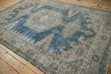 Vintage distressed Veece carpet showing decorative wear across its dusty blue and beige geometric design.