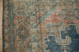 Distressed texture of a vintage Veece carpet showing the pomegranate vine border and dusty denim blue tones.