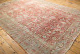 Angled view showing the low pile and decorative wear on a distressed Heriz carpet in ruby and slate blue.