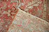 A folded corner of a distressed Heriz carpet reveals the hand-knotted foundation and low pile texture.