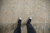 Distressed Heriz carpet, worn pile with faded beige, dusty blue floral and geometric motifs.