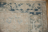 Corner of distressed Heriz carpet showing faded beige, dusty blue, and ivory floral patterns.