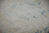 Distressed field of vintage Mehrivan rug showing faded dusty blue and beige floral patterns.