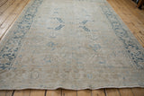 Distressed vintage Mehrivan carpet's muted ivory field with faint blue floral vines and detailed Turtle Samovar border.