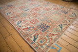 Corner view of a distressed Baktiari carpet showing its panelled field and wide floral border.