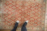 A top-down view of the distressed, low-pile texture on a vintage red Joshegan rug.