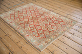 Angled view of a distressed Joshegan rug highlighting its cherry red and ivory quatrefoil pattern.