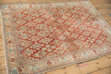 Angled view of a vintage distressed Joshegan rug showing its allover floral pattern.