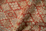 Distressed, hand-knotted pile showing diamond-shaped floral clusters in red, ivory, and blue.